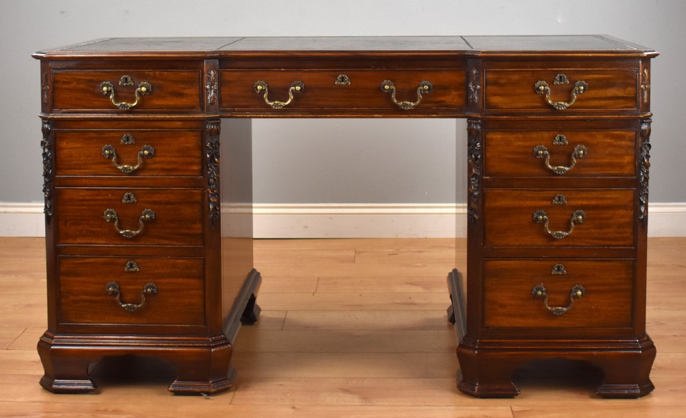 A 19th-century Chippendale style mahogany pedestal desk with a three-section leather inset top, nine drawers, brass handles, and carved pilasters. View II