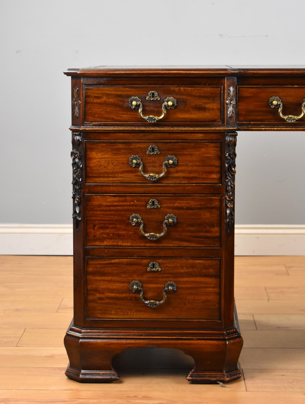 A 19th-century Chippendale style mahogany pedestal desk with a three-section leather inset top, nine drawers, brass handles, and carved pilasters. View III