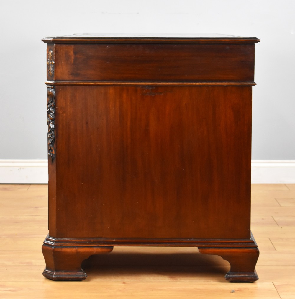 A 19th-century Chippendale style mahogany pedestal desk with a three-section leather inset top, nine drawers, brass handles, and carved pilasters. View VIII