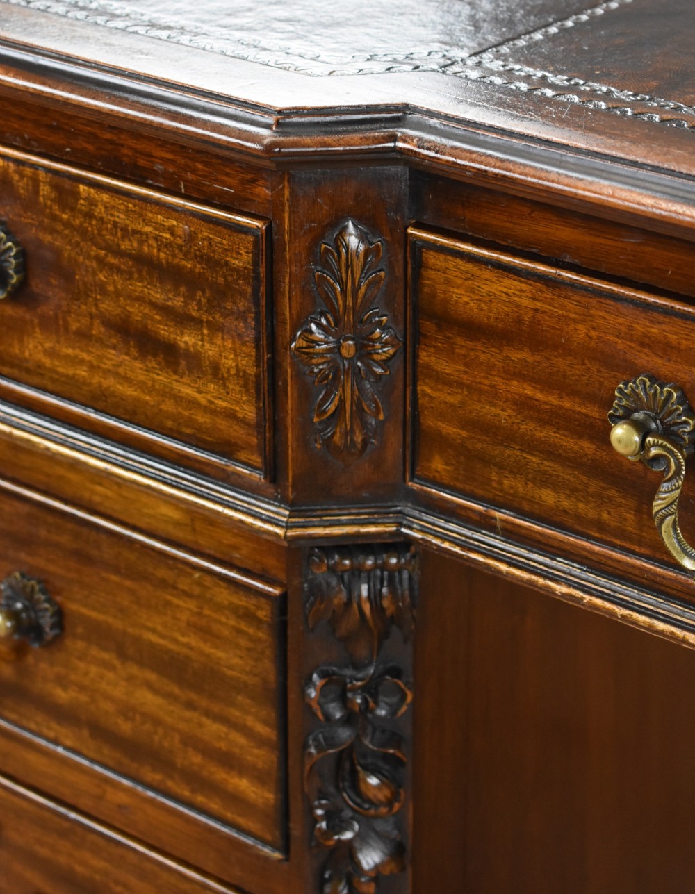 A 19th-century Chippendale style mahogany pedestal desk with a three-section leather inset top, nine drawers, brass handles, and carved pilasters. View XII