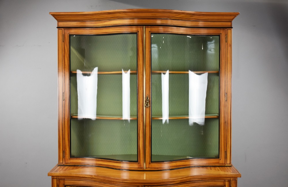A 19th-century satinwood display cabinet featuring a serpentine glazed upper section and inlaid lower cupboard doors. View III