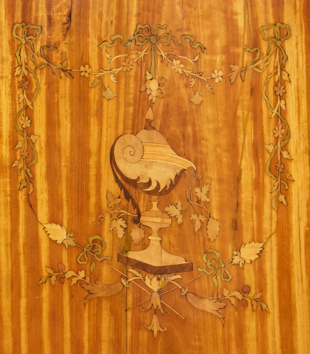 A 19th-century satinwood display cabinet featuring a serpentine glazed upper section and inlaid lower cupboard doors. View VI