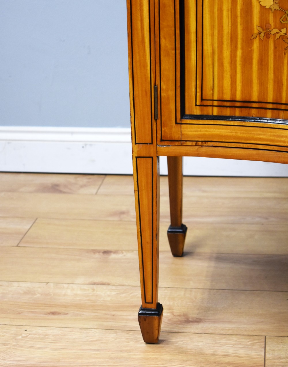 A 19th-century satinwood display cabinet featuring a serpentine glazed upper section and inlaid lower cupboard doors. View VII