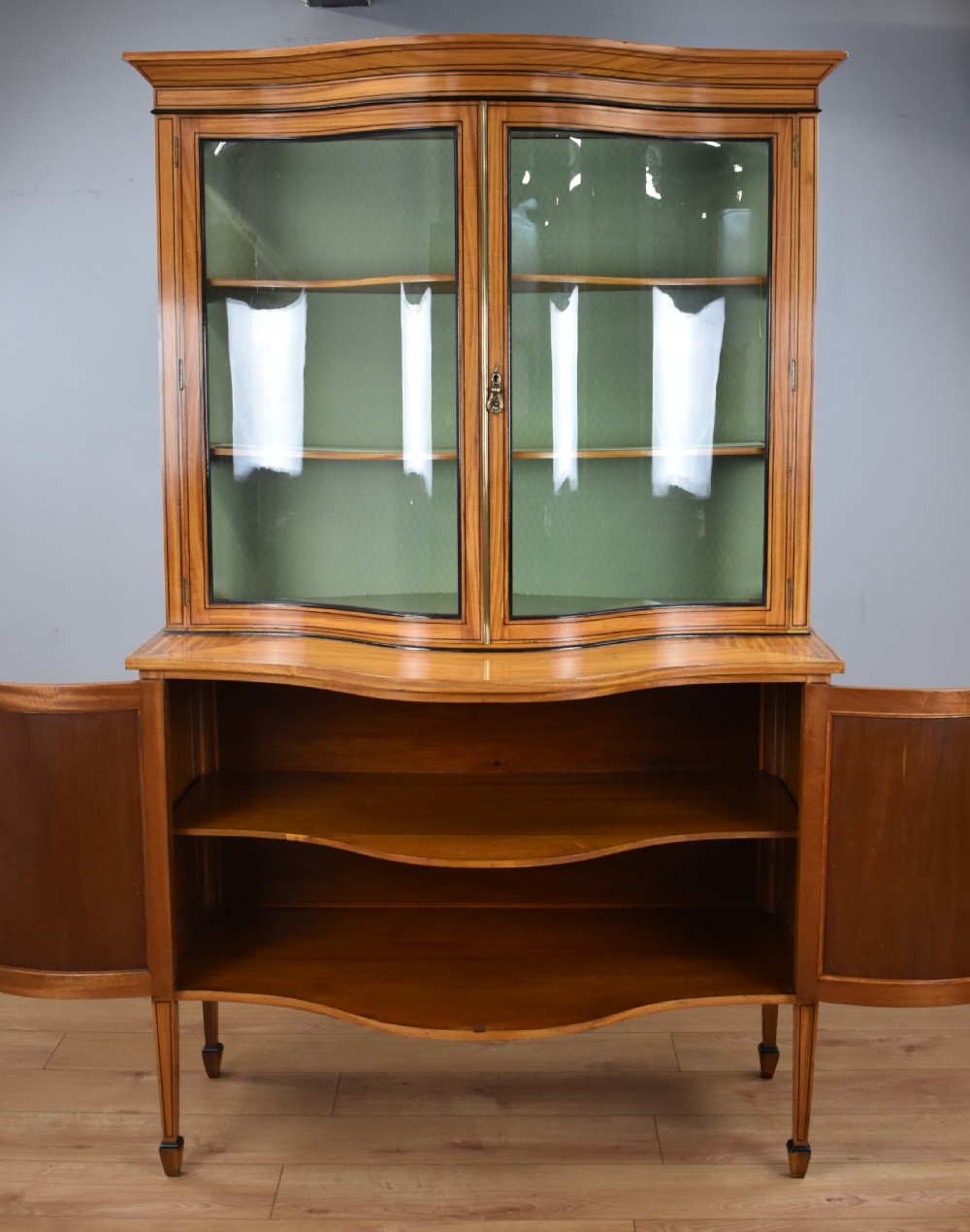 A 19th-century satinwood display cabinet featuring a serpentine glazed upper section and inlaid lower cupboard doors. View VIII