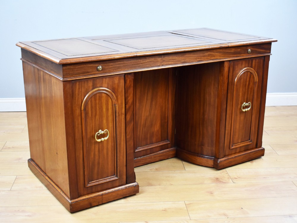 A Victorian mahogany kneehole desk with three leather-inlaid writing panels, twin pedestals featuring arched mouldings, and brass handles. View II