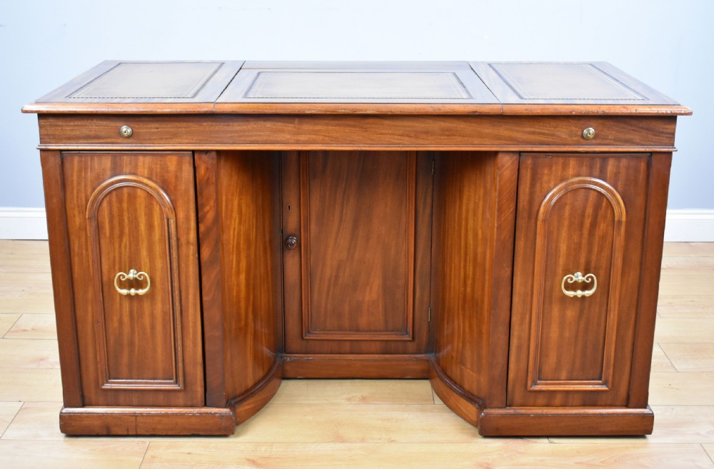A Victorian mahogany kneehole desk with three leather-inlaid writing panels, twin pedestals featuring arched mouldings, and brass handles. View III