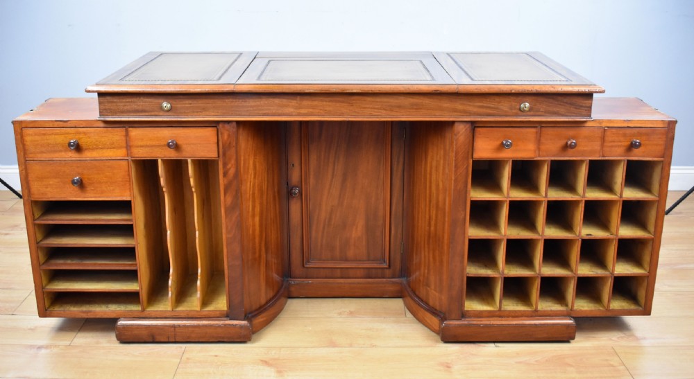 A Victorian mahogany kneehole desk with three leather-inlaid writing panels, twin pedestals featuring arched mouldings, and brass handles. View IV