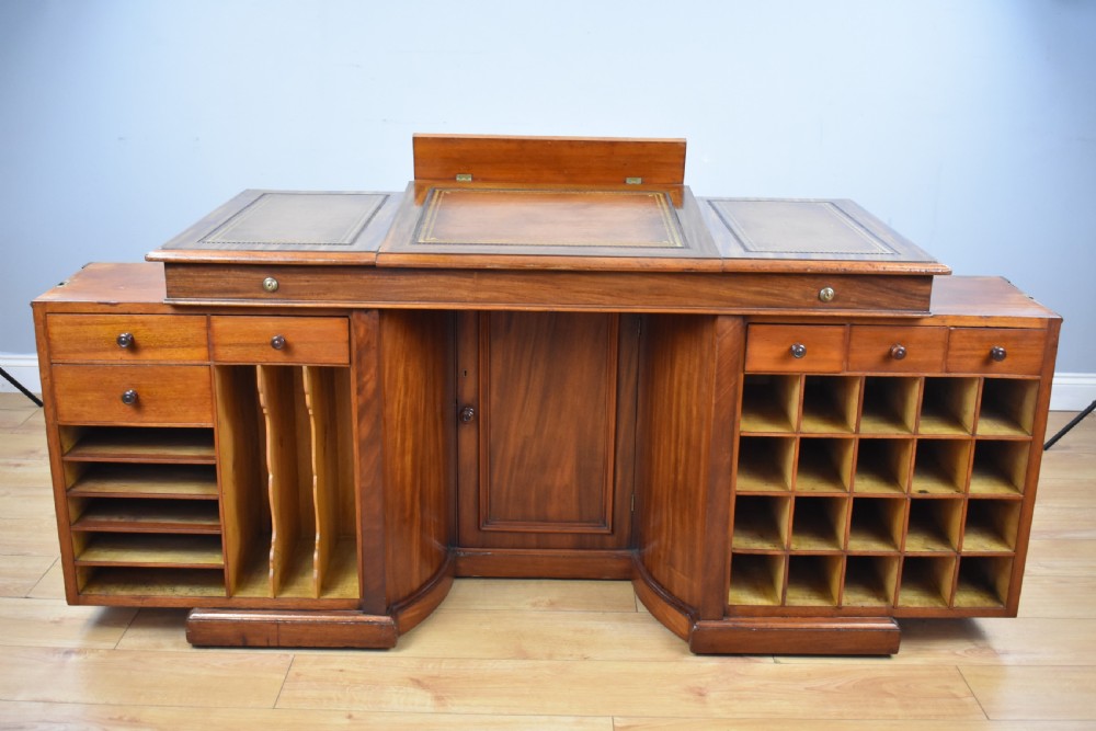A Victorian mahogany kneehole desk with three leather-inlaid writing panels, twin pedestals featuring arched mouldings, and brass handles. View VII