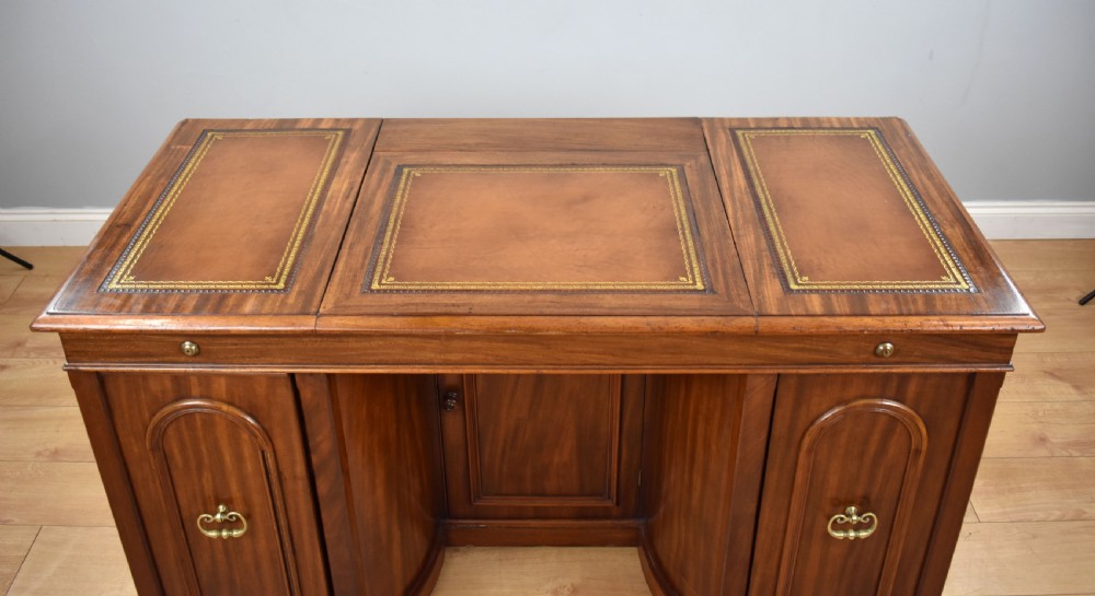 A Victorian mahogany kneehole desk with three leather-inlaid writing panels, twin pedestals featuring arched mouldings, and brass handles. View XI