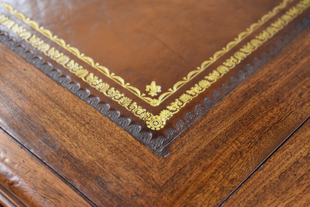 A Victorian mahogany kneehole desk with three leather-inlaid writing panels, twin pedestals featuring arched mouldings, and brass handles. View XII