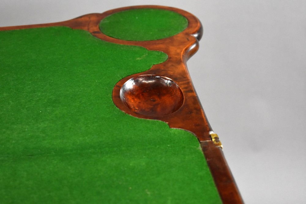 An 18th-century George II Irish mahogany fold-over card table with carved shell knees, a scalloped apron, and slender cabriole legs. View XII