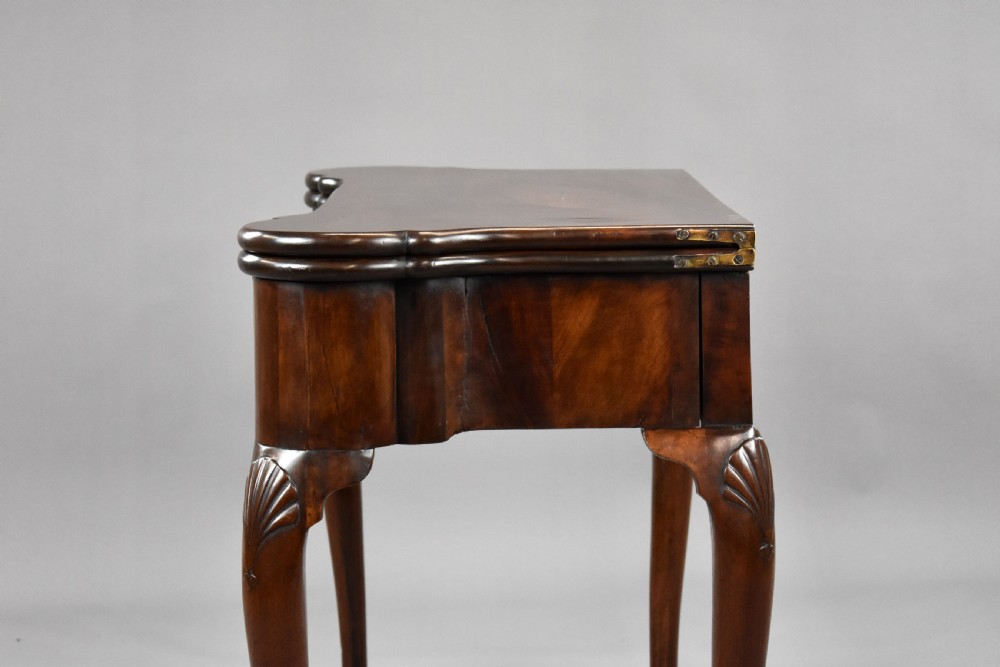 An 18th-century George II Irish mahogany fold-over card table with carved shell knees, a scalloped apron, and slender cabriole legs. View XVI