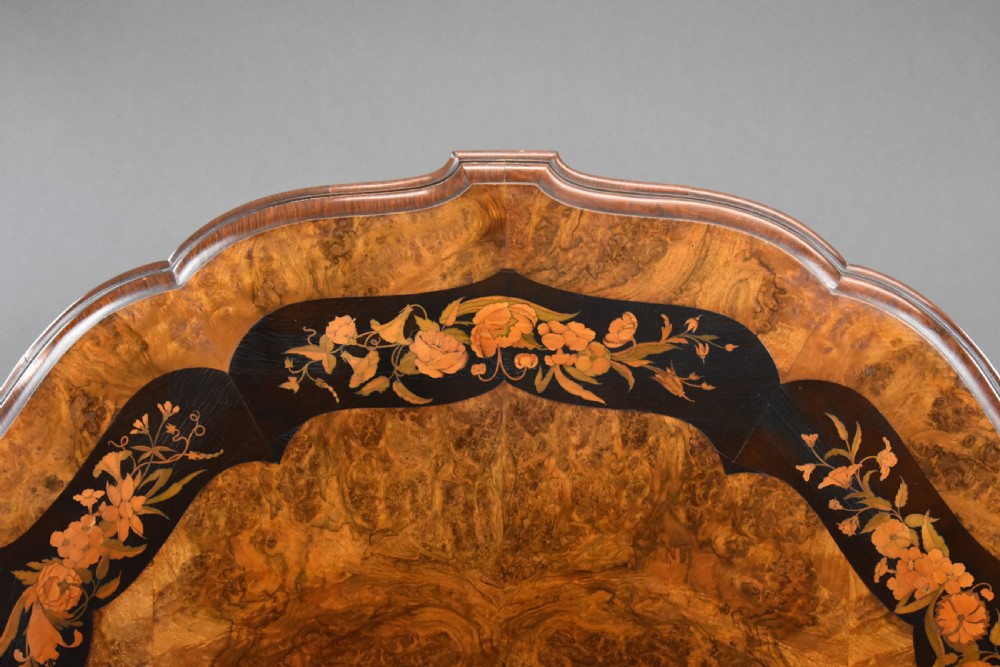 A Victorian burr walnut tilt-top breakfast table featuring a scalloped edge, intricate floral marquetry inlay border, and a carved four-star pedestal base. View IV