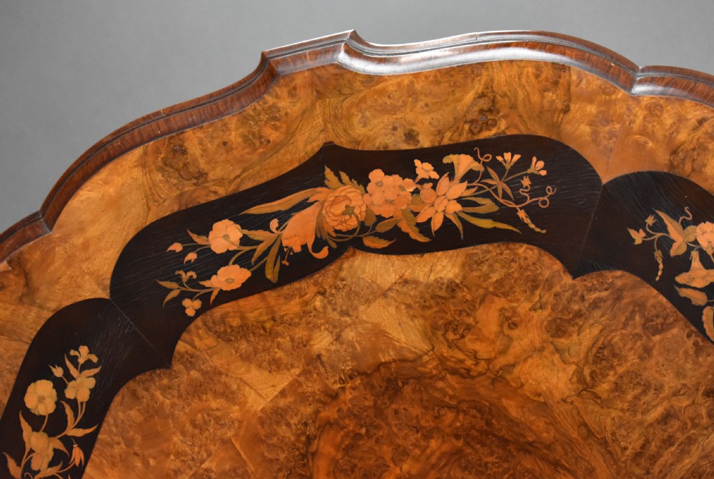 A Victorian burr walnut tilt-top breakfast table featuring a scalloped edge, intricate floral marquetry inlay border, and a carved four-star pedestal base. View VIII