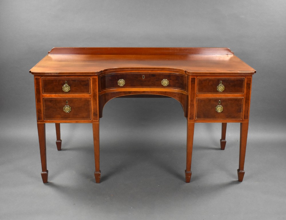 A nineteenth-century mahogany sideboard featuring a central kneehole arch, five inlaid drawers with brass rosette pull handles, and square tapered legs terminating in spade feet.