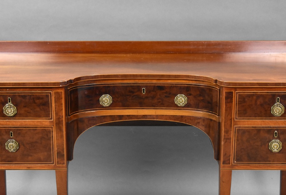 A nineteenth-century mahogany sideboard featuring a central kneehole arch, five inlaid drawers with brass rosette pull handles, and square tapered legs terminating in spade feet. View III