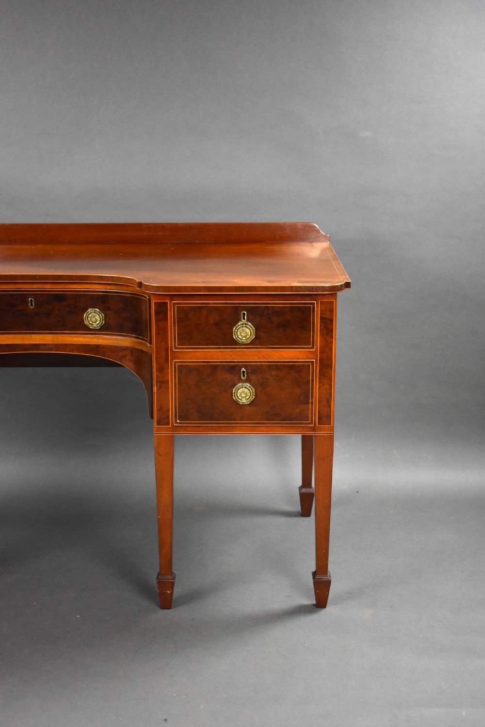 A nineteenth-century mahogany sideboard featuring a central kneehole arch, five inlaid drawers with brass rosette pull handles, and square tapered legs terminating in spade feet. View IV