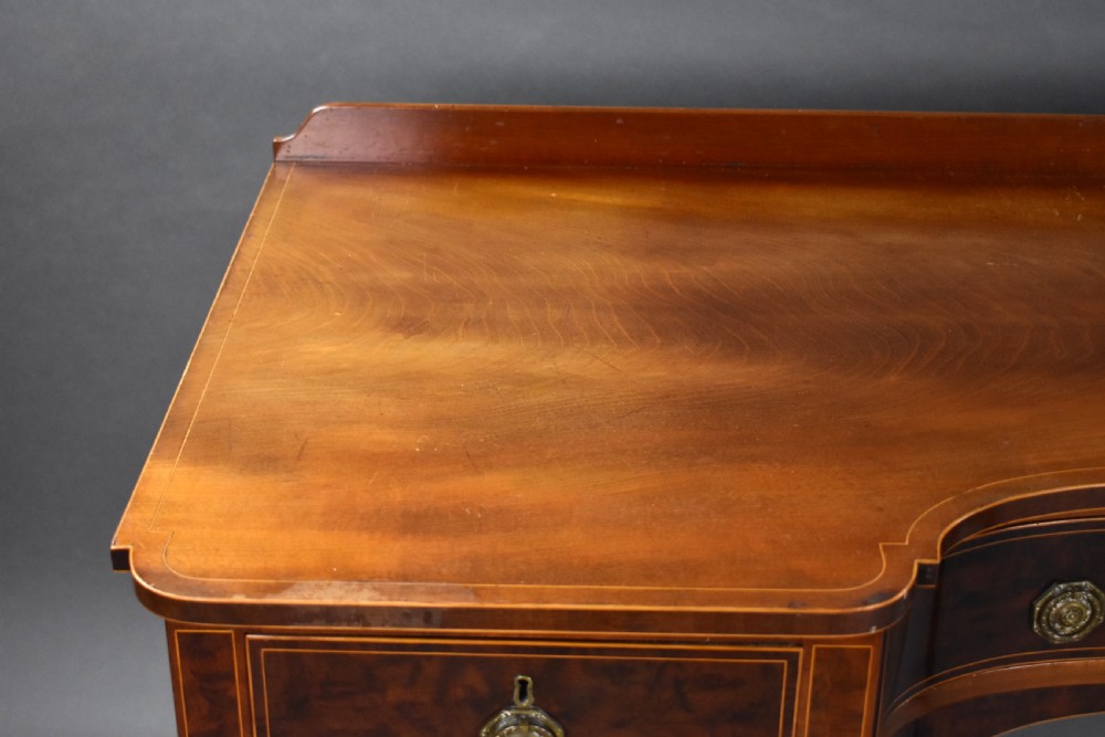 A nineteenth-century mahogany sideboard featuring a central kneehole arch, five inlaid drawers with brass rosette pull handles, and square tapered legs terminating in spade feet. View VIII