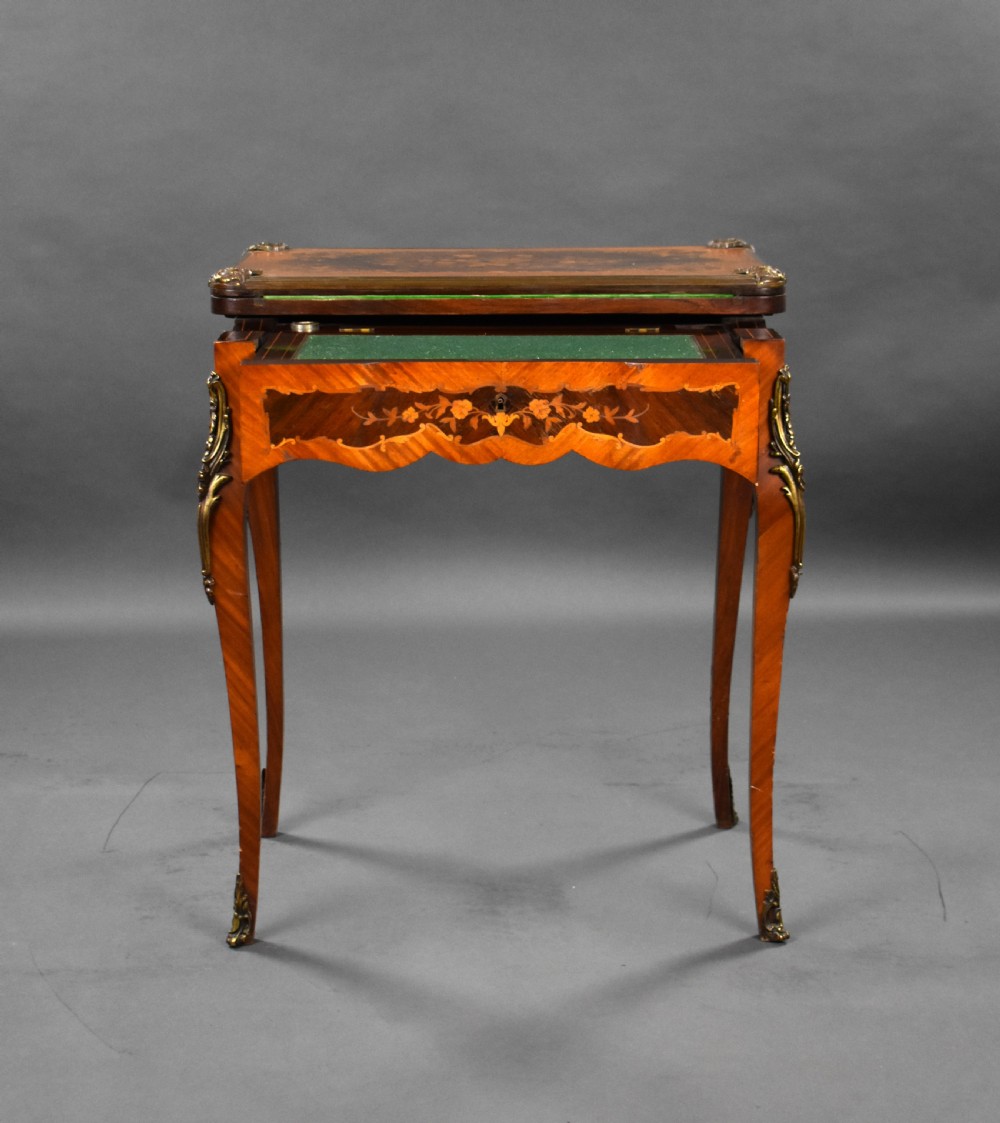 A Victorian French-style marquetry card table featuring slender cabriole legs with brass mounts and intricate floral inlay along the serpentine apron. View V