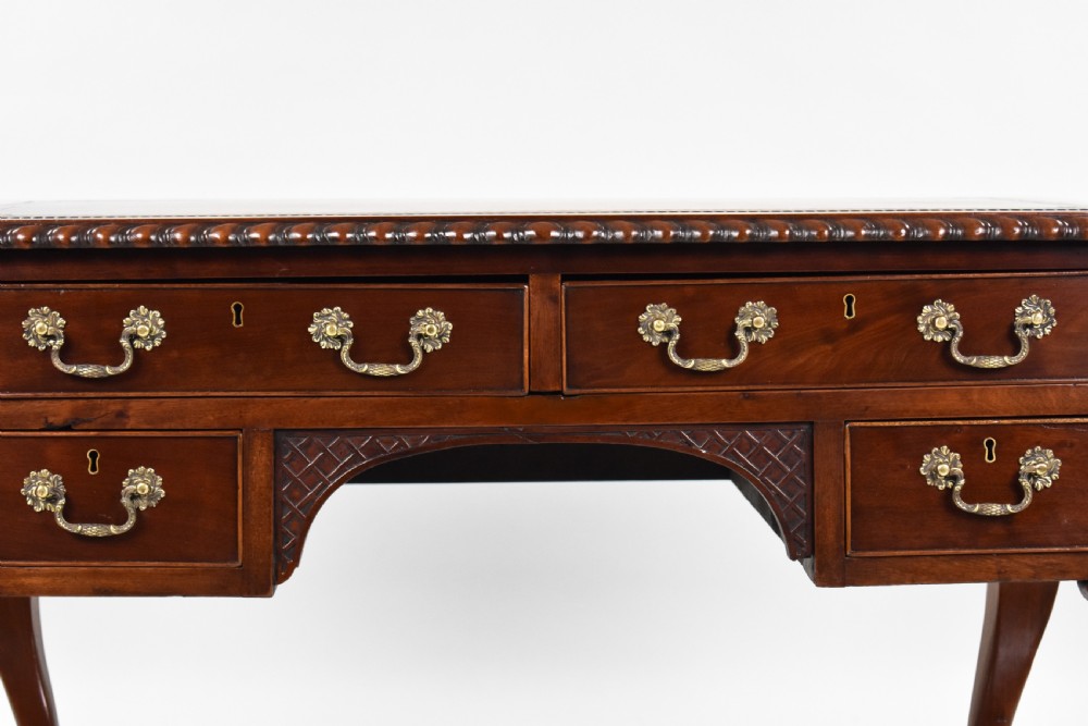 A dark brown mahogany Chippendale style writing table featuring cabriole legs with claw and ball feet, carved knees, gadrooned edging, and drawers with brass swan-neck handles. View IV