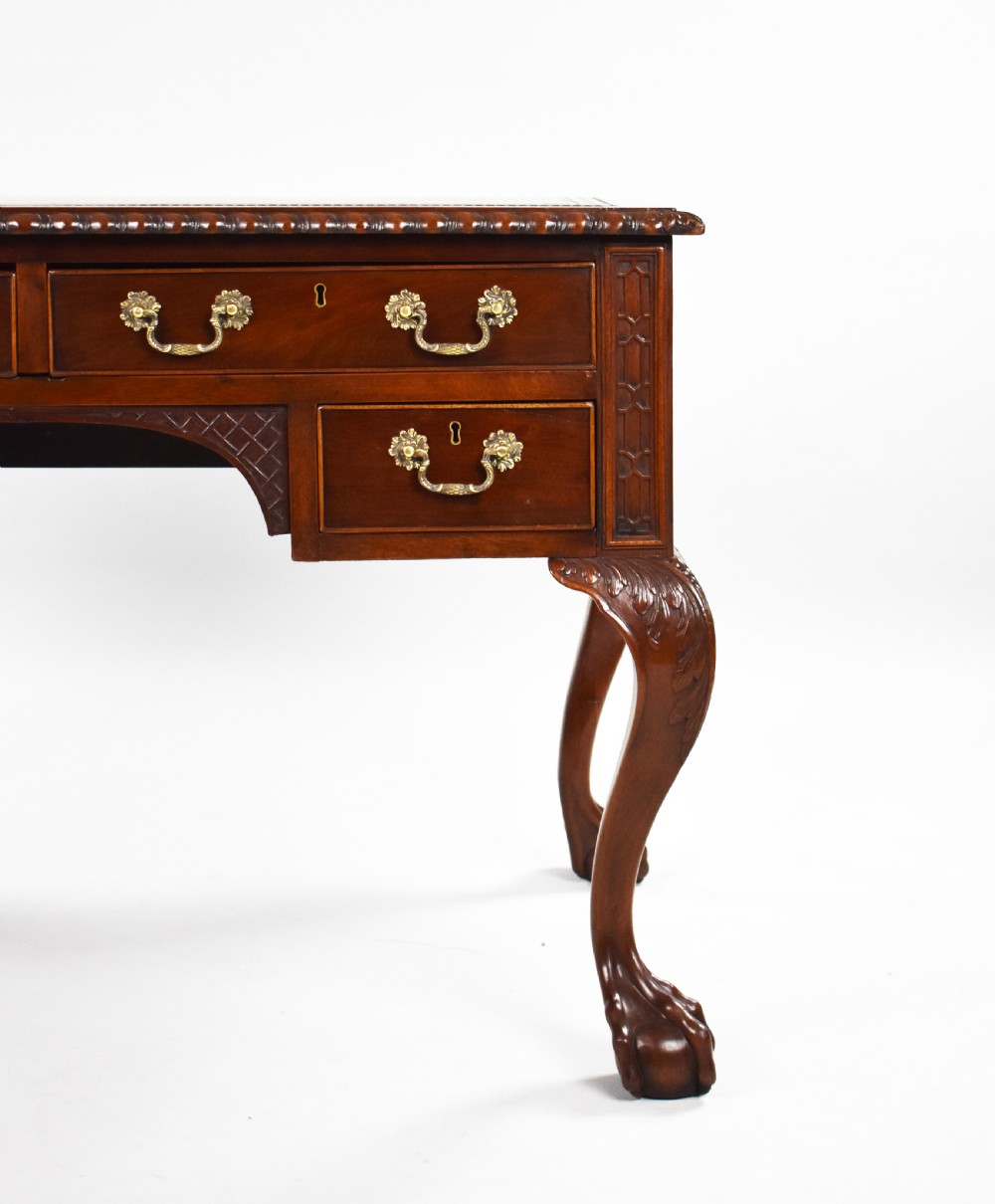 A dark brown mahogany Chippendale style writing table featuring cabriole legs with claw and ball feet, carved knees, gadrooned edging, and drawers with brass swan-neck handles. View V
