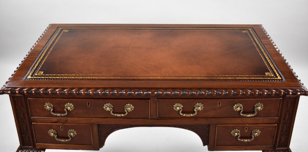 A dark brown mahogany Chippendale style writing table featuring cabriole legs with claw and ball feet, carved knees, gadrooned edging, and drawers with brass swan-neck handles. View IX