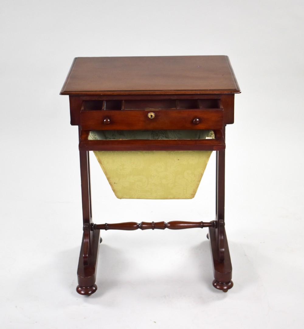 A Victorian mahogany work table featuring a single drawer with wooden knobs, a suspended yellow patterned fabric basket below, and a turned stretcher base set on castors. View VI