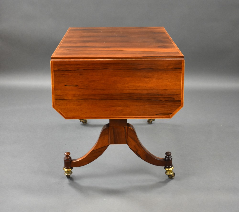 An early 19th-century Regency rosewood sofa table with drop leaves, boxwood stringing, two drawers, turned legs, and brass castors. View VII