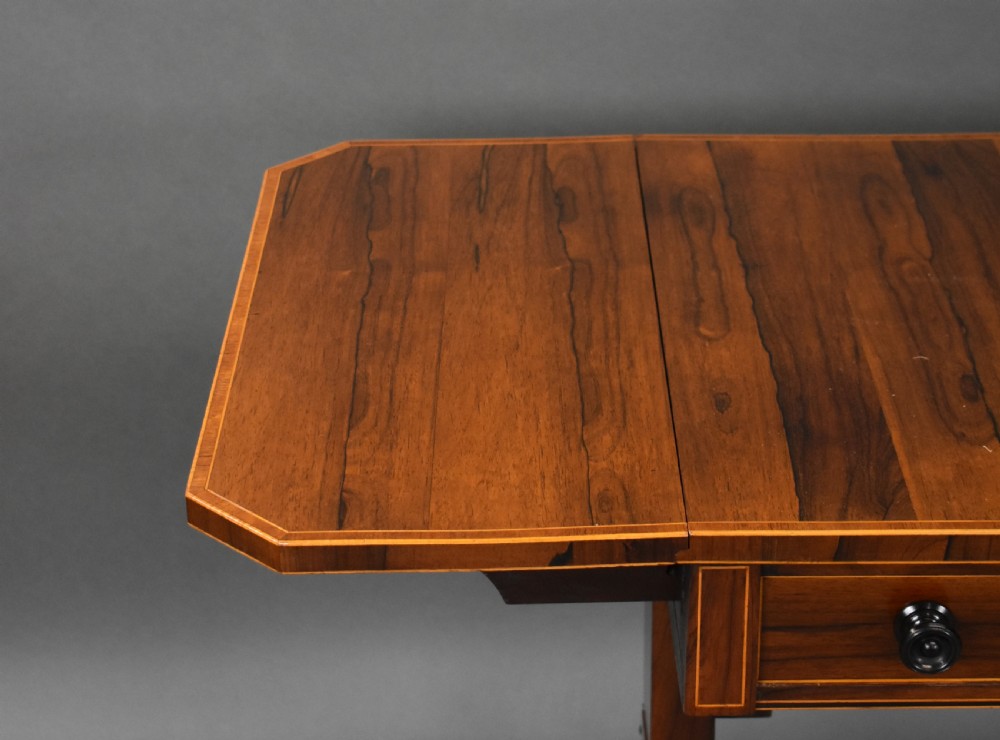 An early 19th-century Regency rosewood sofa table with drop leaves, boxwood stringing, two drawers, turned legs, and brass castors. View IX