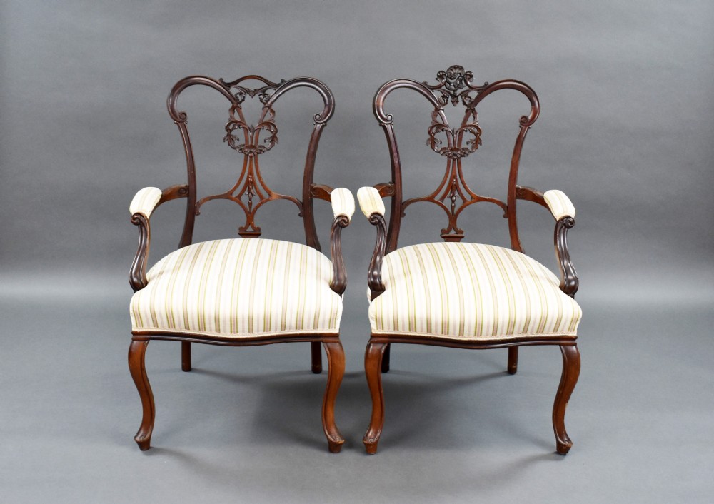 A pair of Victorian carved mahogany armchairs featuring pierced splat backs, padded armrests, and striped upholstery over cabriole legs. View III