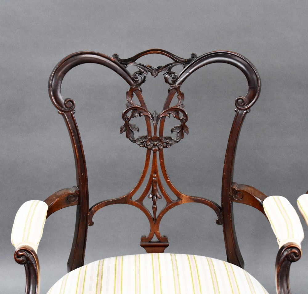 A pair of Victorian carved mahogany armchairs featuring pierced splat backs, padded armrests, and striped upholstery over cabriole legs. View V