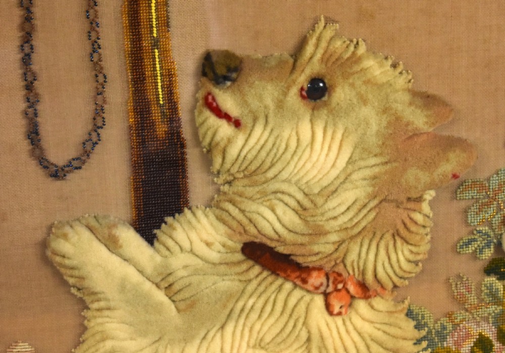 A dark carved wood Victorian fire screen framed around a central needlepoint panel depicting a parrot perched above two dogs. View XIV