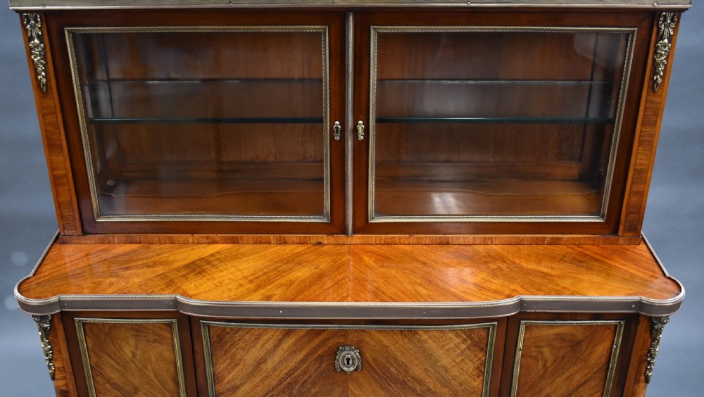 A 19th-century French walnut cabinet featuring a two-door glazed top display section above a lower storage unit with drawers and brass mounts, raised on tapered legs. View IX