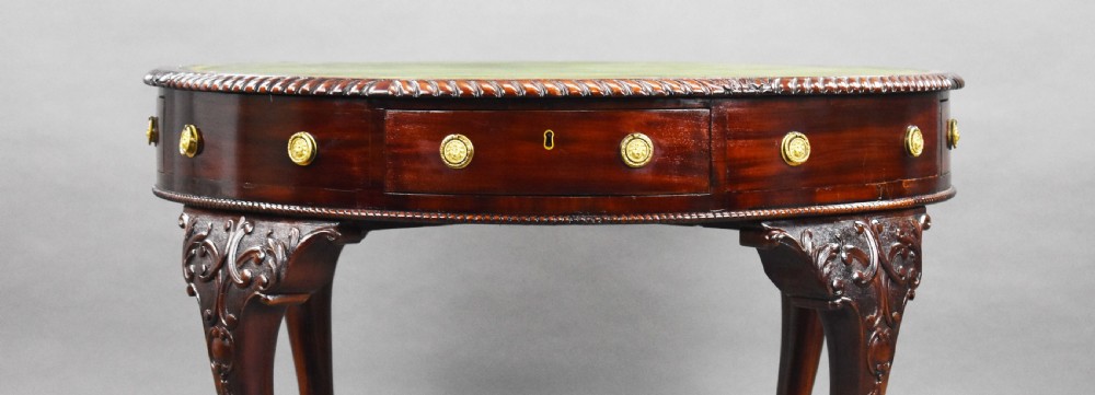 An Edwardian mahogany drum table featuring a green inset leather top, carved cabriole legs with ball-and-claw feet, and circular brass handles. View III