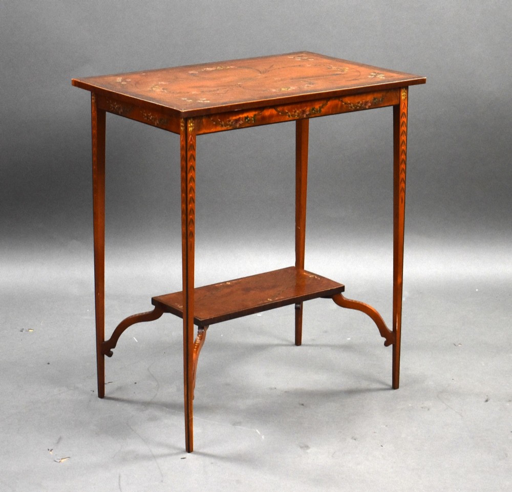 An Edwardian rectangular satinwood occasional table featuring tapered legs, an undershelf, and hand-painted floral motifs across the top and apron.