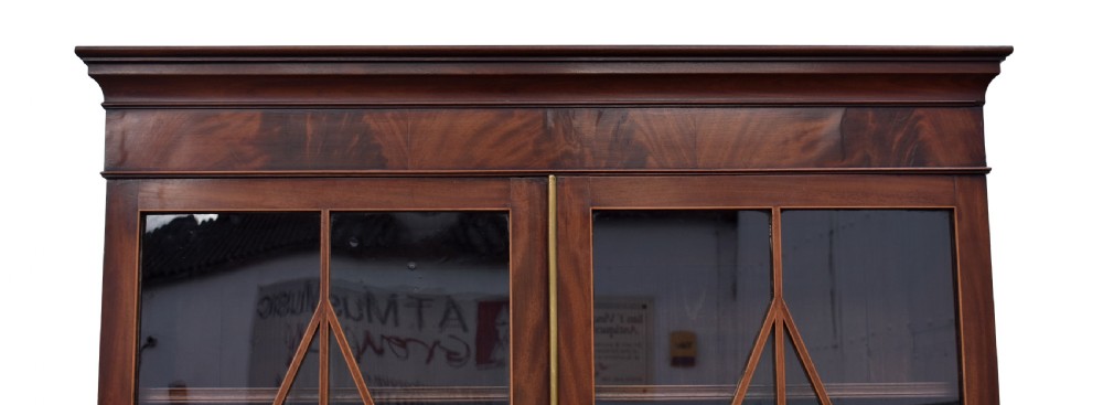 A William IV flame mahogany secretaire bookcase featuring a double glazed door upper section with diamond glazing bars over a chest of drawers with carved feet. View VIII