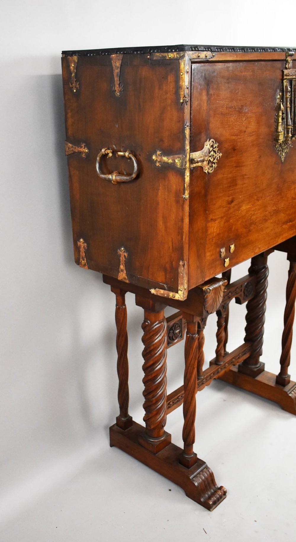 A 17th-century Spanish walnut Bargueno cabinet featuring an intricate brass lockplate and side mounts, resting on an ornate barley-twist wooden stand. View II