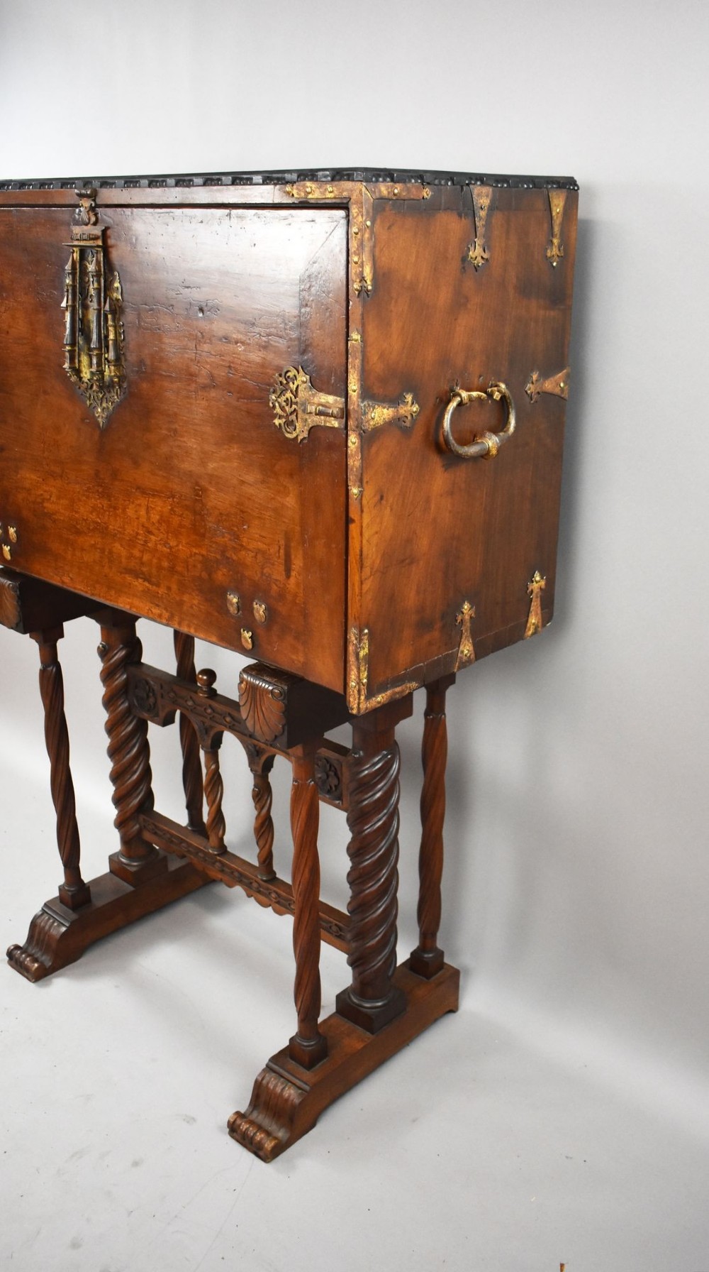A 17th-century Spanish walnut Bargueno cabinet featuring an intricate brass lockplate and side mounts, resting on an ornate barley-twist wooden stand. View III