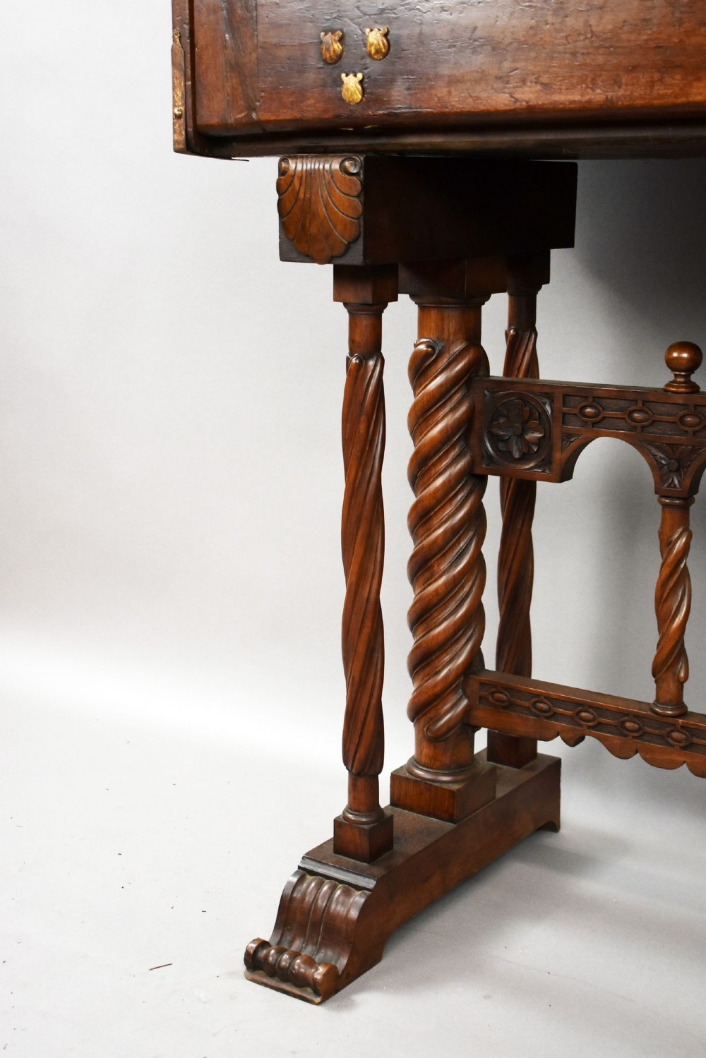 A 17th-century Spanish walnut Bargueno cabinet featuring an intricate brass lockplate and side mounts, resting on an ornate barley-twist wooden stand. View VII
