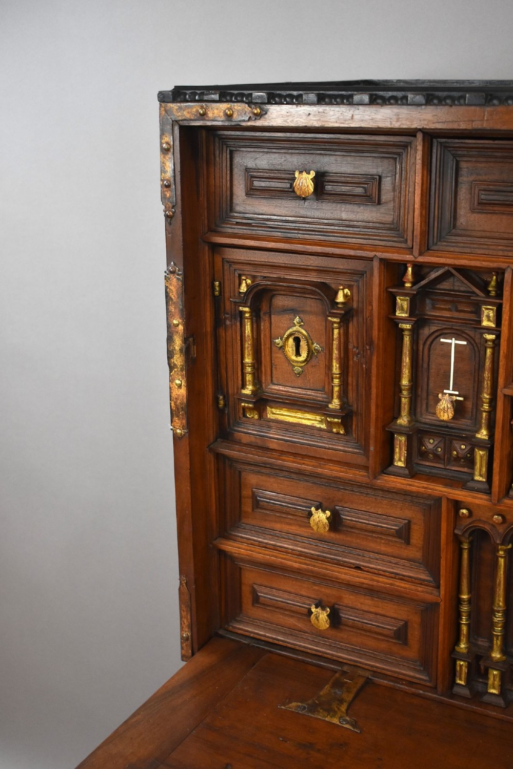 A 17th-century Spanish walnut Bargueno cabinet featuring an intricate brass lockplate and side mounts, resting on an ornate barley-twist wooden stand. View XI