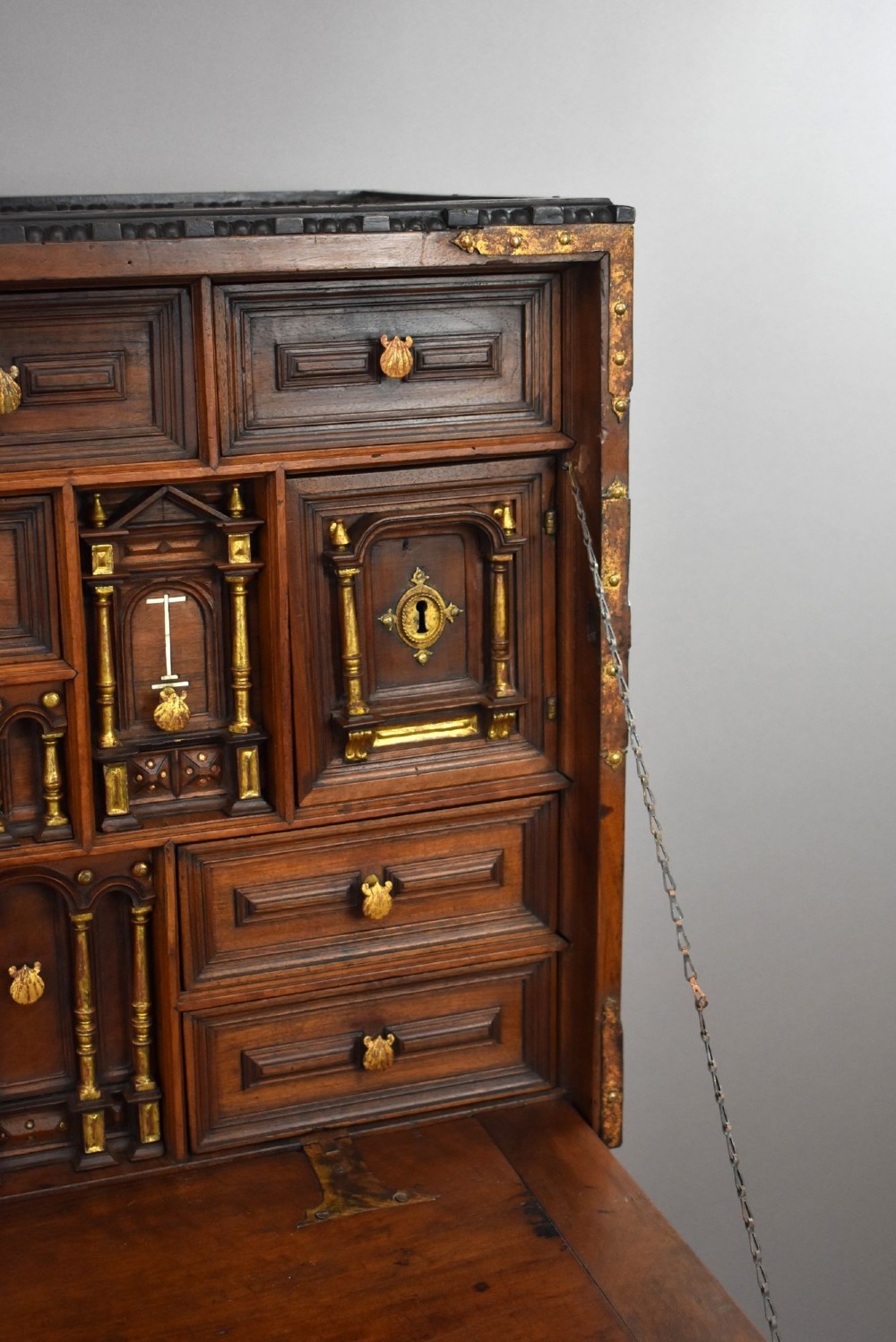 A 17th-century Spanish walnut Bargueno cabinet featuring an intricate brass lockplate and side mounts, resting on an ornate barley-twist wooden stand. View XII