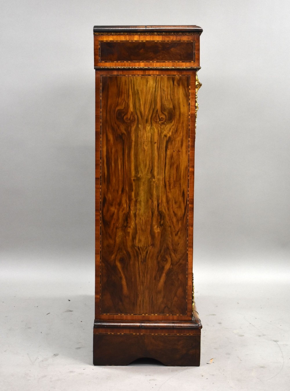 A Victorian burr walnut pier cabinet featuring a single glazed door, boxwood marquetry stringing, and ornate gilt brass mounts. View III