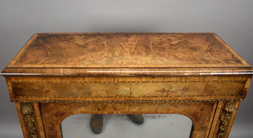 A Victorian burr walnut pier cabinet featuring a single glazed door, boxwood marquetry stringing, and ornate gilt brass mounts. View IX