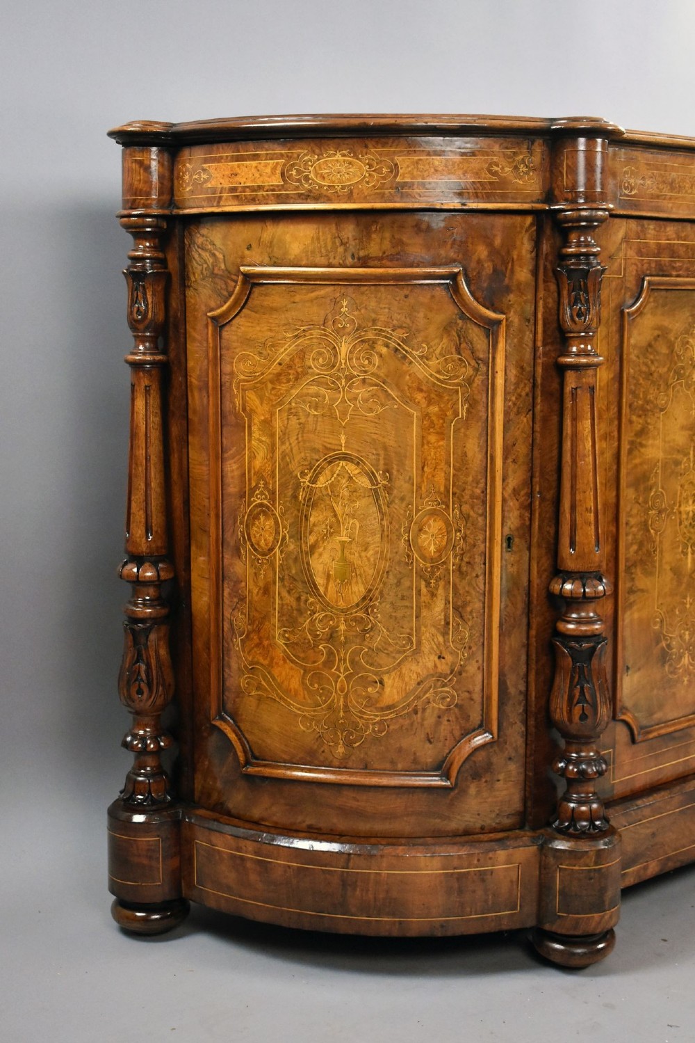 A Victorian burr walnut credenza featuring elaborate floral marquetry inlays on two central doors, flanked by turned columns and rounded side panels. View II