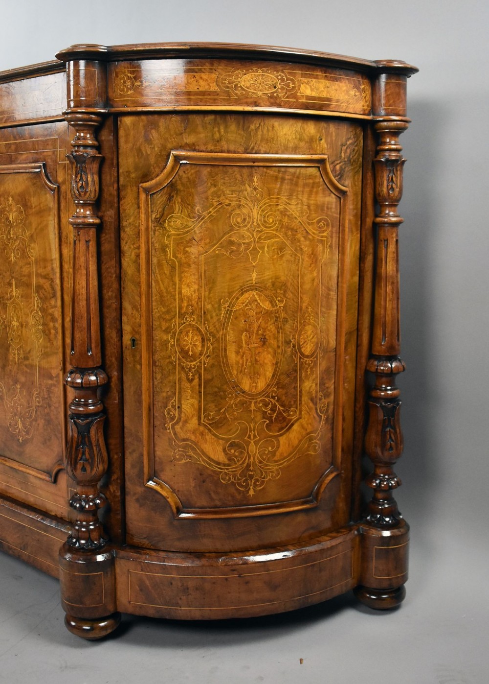 A Victorian burr walnut credenza featuring elaborate floral marquetry inlays on two central doors, flanked by turned columns and rounded side panels. View IV