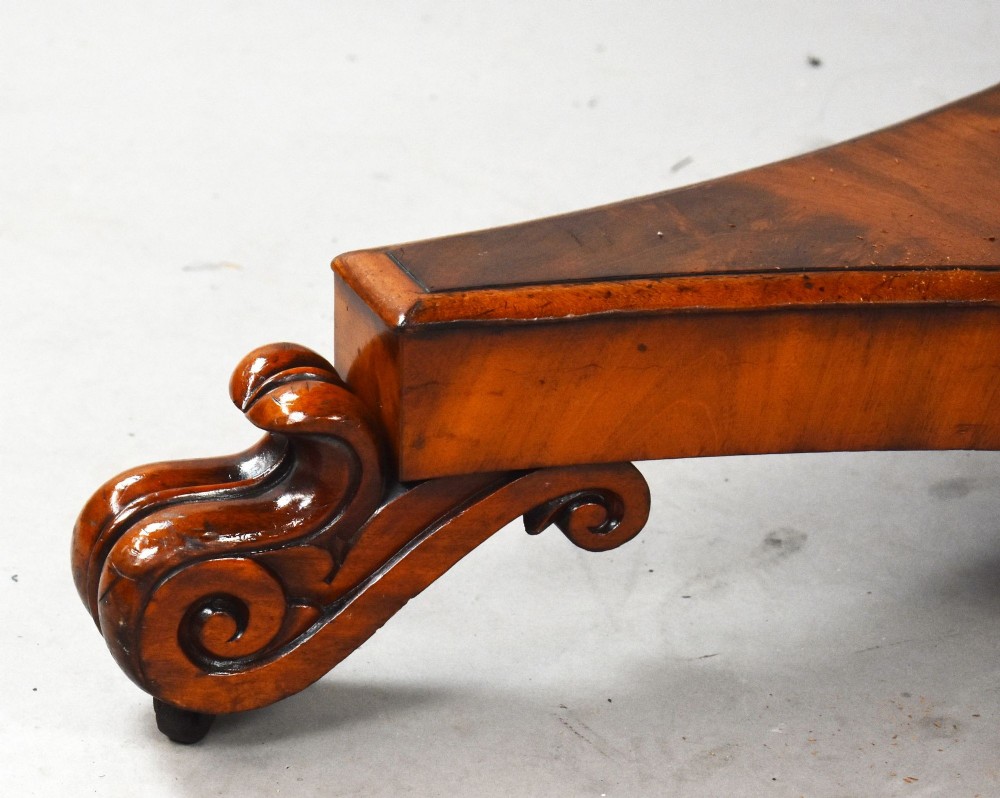 A circular William IV flame mahogany tilt-top breakfast table with a starburst veneer pattern shown in a vertical tilted position on a triform pedestal base with carved scroll feet. View VII
