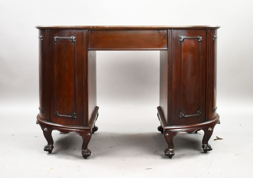 A dark mahogany kidney-shaped writing desk with a gilded leather top insert, twin pedestals featuring ornate brass handles, and cabriole legs ending in claw-and-ball feet. View V