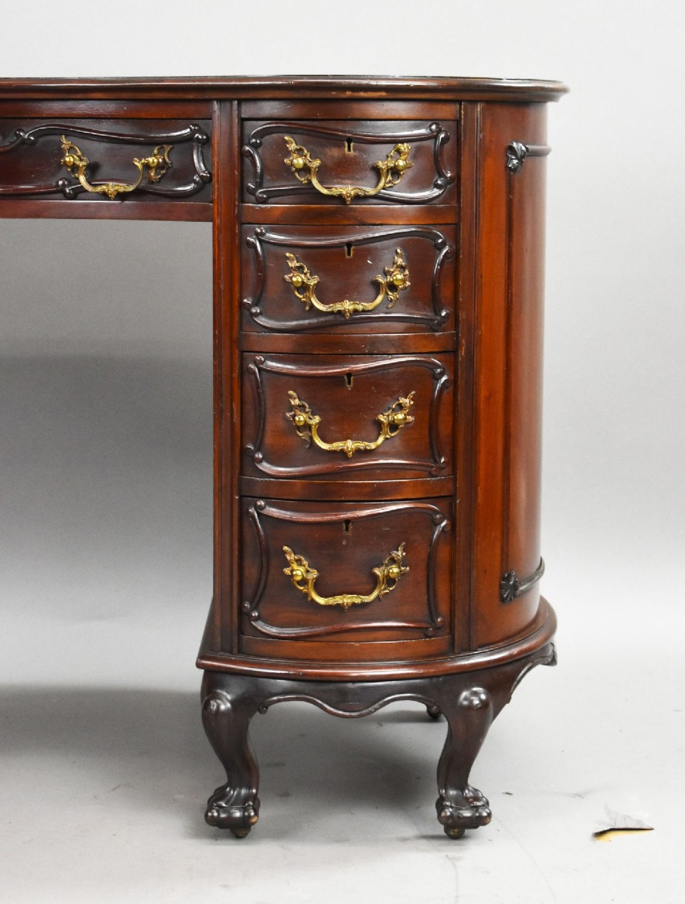 A dark mahogany kidney-shaped writing desk with a gilded leather top insert, twin pedestals featuring ornate brass handles, and cabriole legs ending in claw-and-ball feet. View VIII