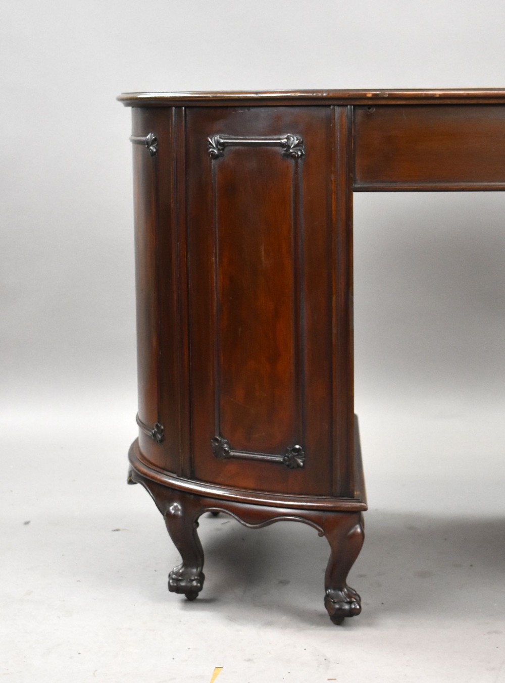 A dark mahogany kidney-shaped writing desk with a gilded leather top insert, twin pedestals featuring ornate brass handles, and cabriole legs ending in claw-and-ball feet. View IX