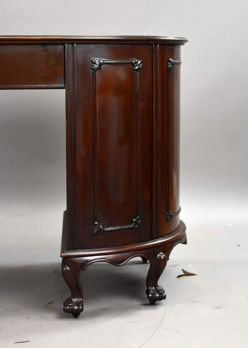 A dark mahogany kidney-shaped writing desk with a gilded leather top insert, twin pedestals featuring ornate brass handles, and cabriole legs ending in claw-and-ball feet. View X